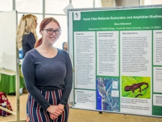Zoology student posing in front of her poster at IdeaFest 2019